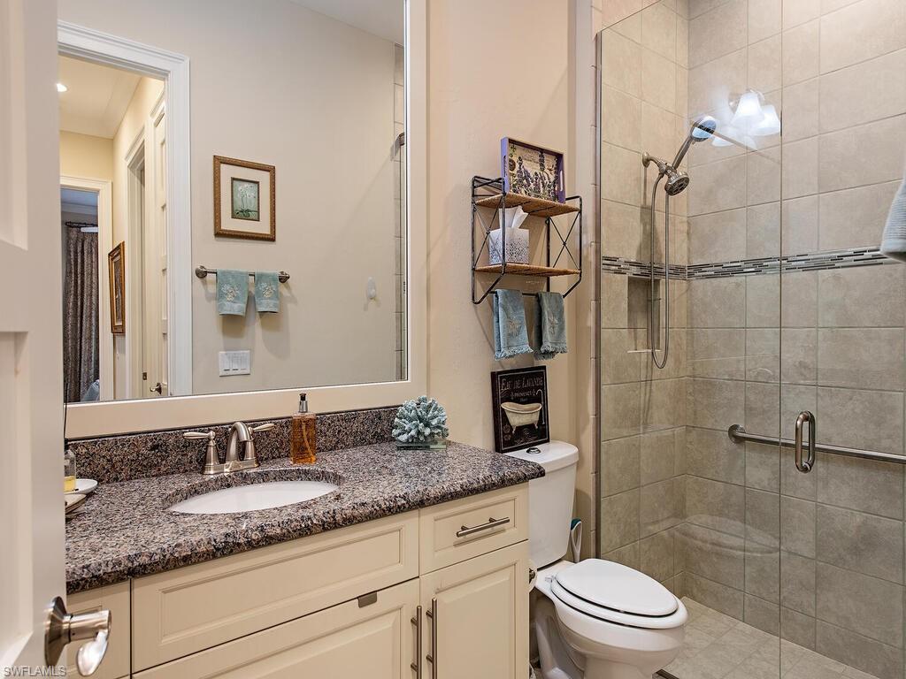 6822 Bequia Way Naples, FL 34113 - Photo 11 of 28 a bathroom with a granite countertop sink a toilet and shower