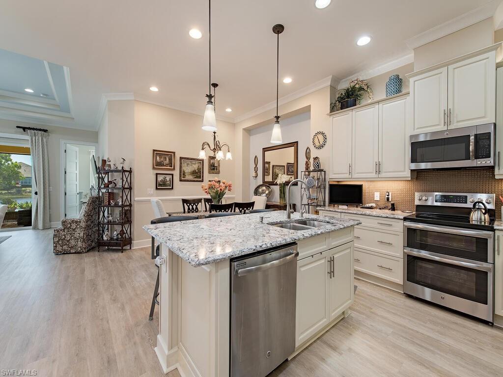 6822 Bequia Way Naples, FL 34113 - Photo 4 of 28 a kitchen with stainless steel appliances granite countertop a stove oven and a sink