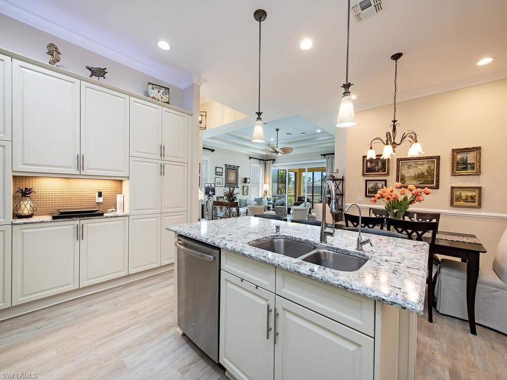 6822 Bequia Way Naples, FL 34113 - Photo 5 of 28 a kitchen with stainless steel appliances granite countertop a sink a oven a stove a dining table and chairs