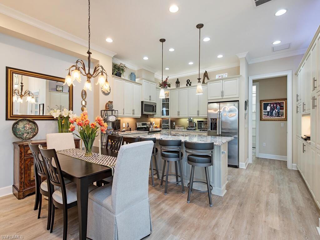 6822 Bequia Way Naples, FL 34113 - Photo 6 of 28 a dining room with stainless steel appliances kitchen island a table and chairs