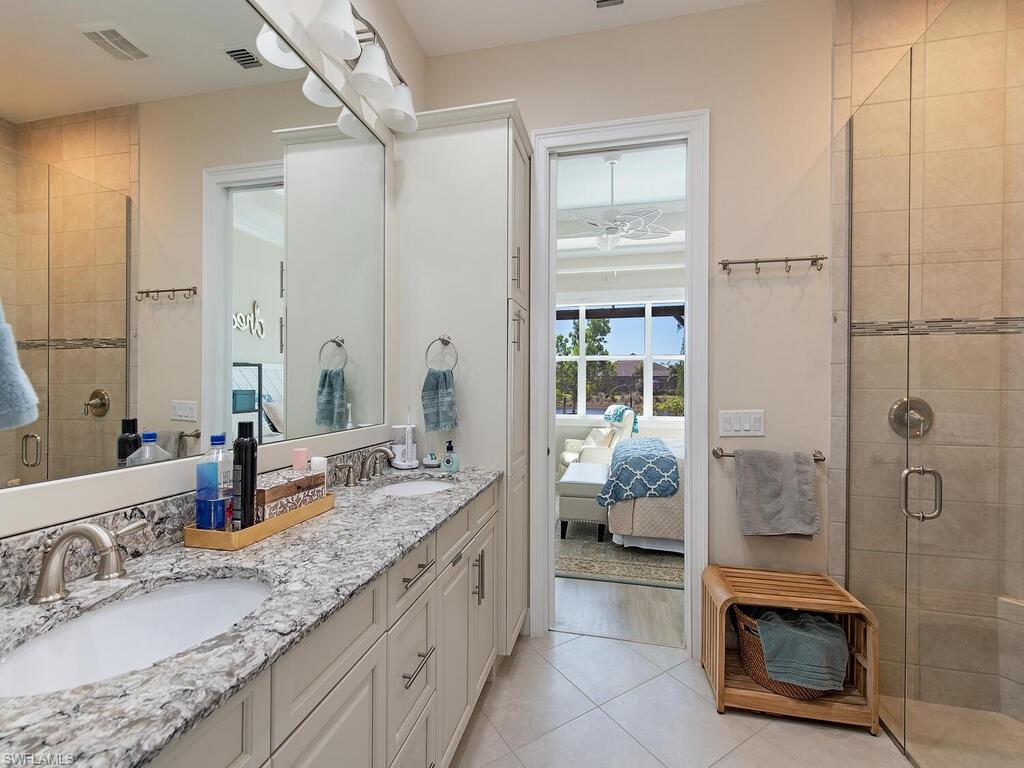 6822 Bequia Way Naples, FL 34113 - Photo 9 of 28 a en suite bathroom with a granite countertop sink and a mirror