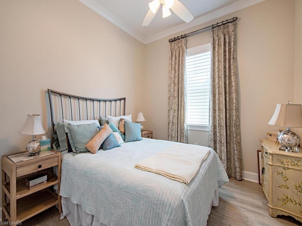 6822 Bequia Way Naples, FL 34113 - Photo 10 of 28 a bedroom with a bed and wooden floor
