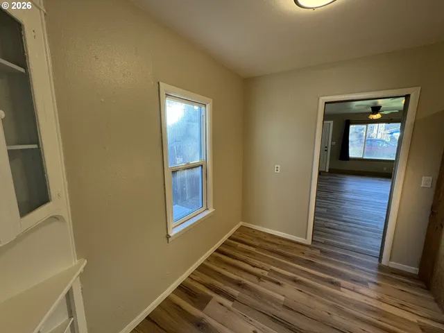 a view of an empty room with wooden floor and a window