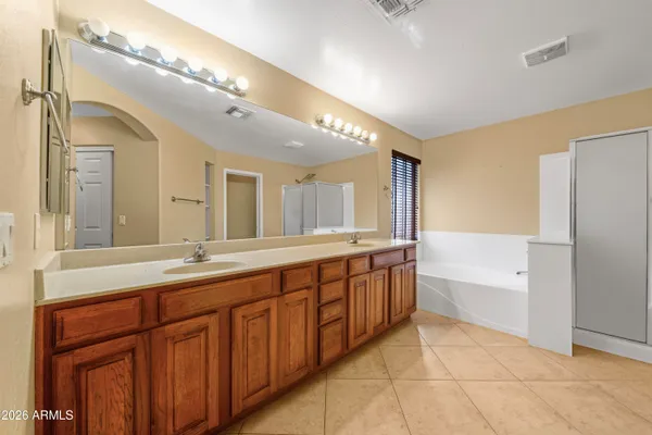 a spacious bathroom with a granite countertop double vanity sink a mirror and a bathtub