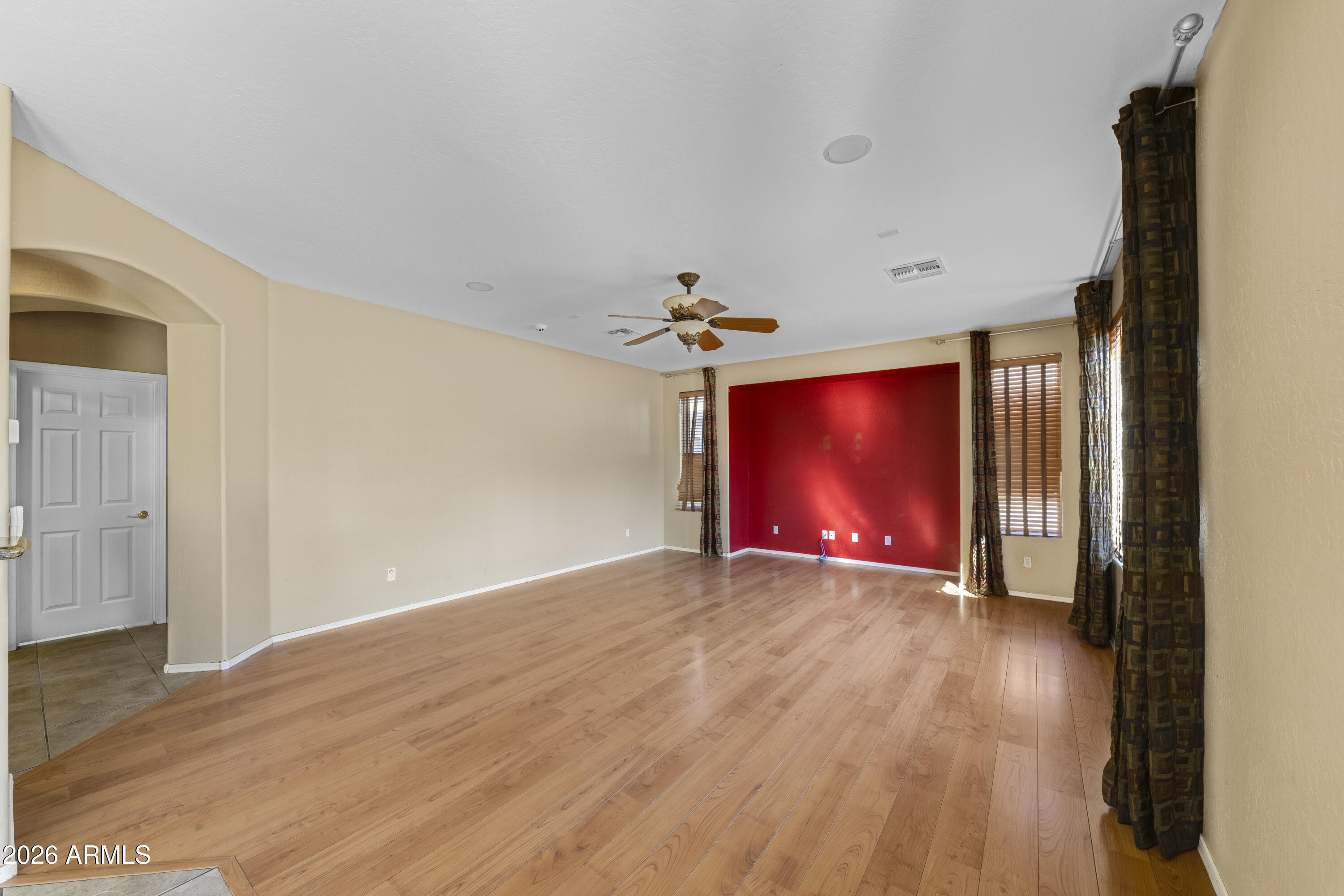 1813 East Beverly Road Phoenix, AZ 85042 - Photo 9 of 32 an empty room with wooden floor chandelier fan and windows