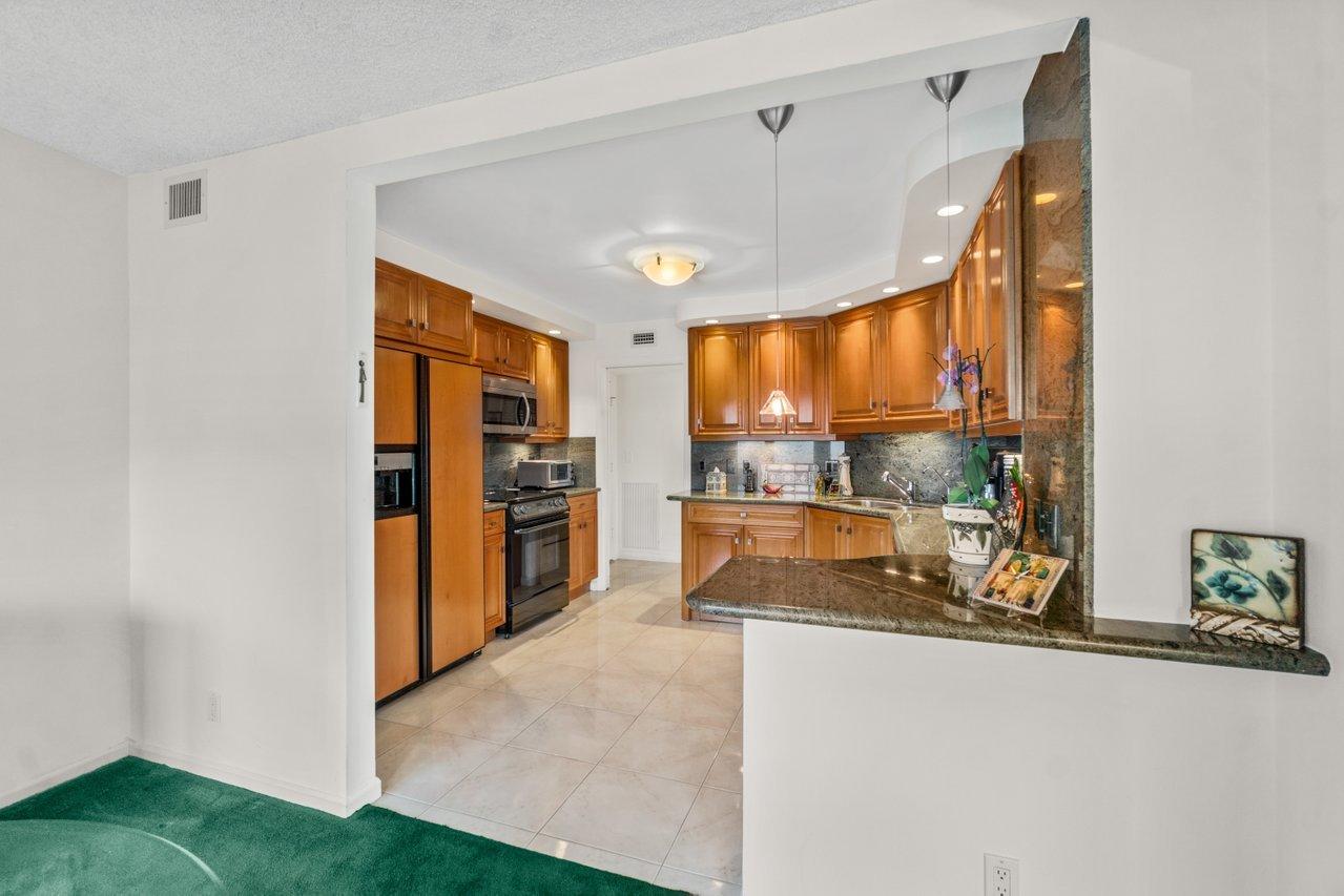 2066 North Ocean Boulevard, Unit 4NW Boca Raton, FL 33431 - Photo 11 of 31 a open kitchen with kitchen island a large window cabinets and stainless steel appliances