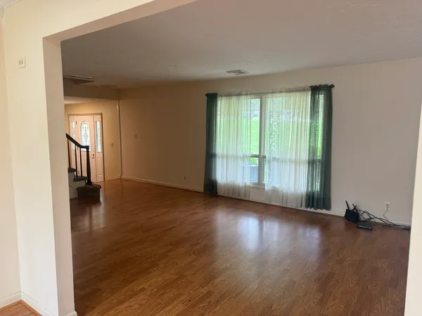 a view of an empty room with wooden floor and stairs