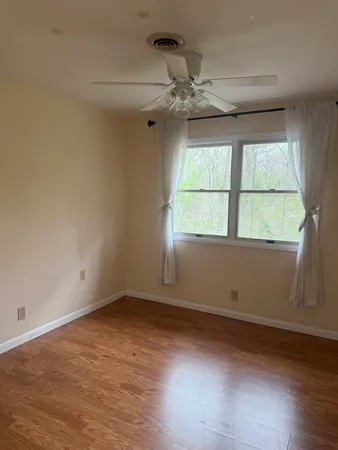 an empty room with wooden floor closet and windows