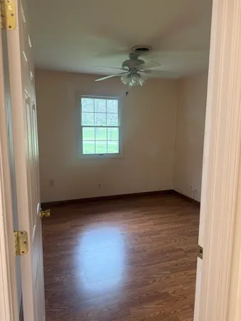 an empty room with wooden floor cabinet and windows