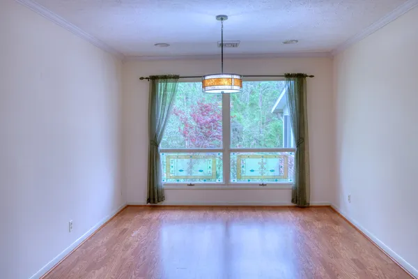 a view of an empty room with window and wooden floor