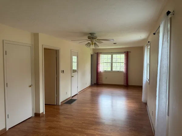 an empty room with wooden floor and windows
