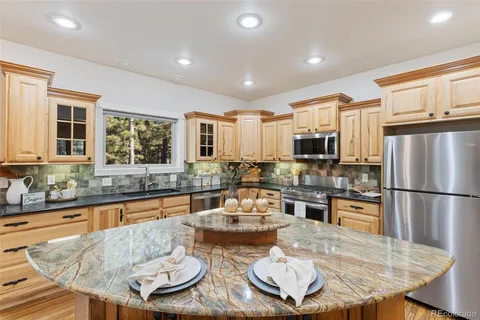 a kitchen with granite countertop stainless steel appliances a sink and a refrigerator