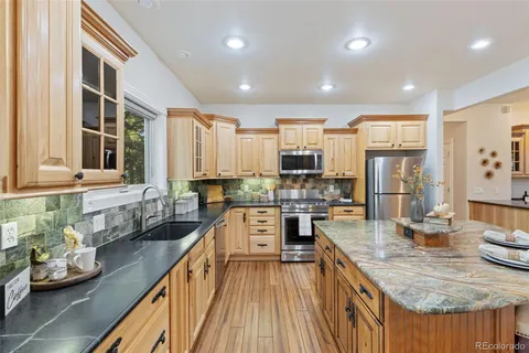 a kitchen with stainless steel appliances granite countertop sink stove refrigerator and wooden floor