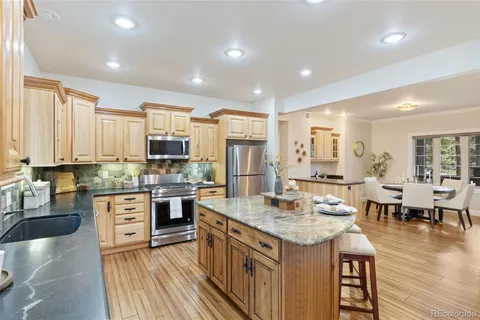 a kitchen with stainless steel appliances granite countertop a stove top oven a sink dishwasher and white cabinets with wooden floor
