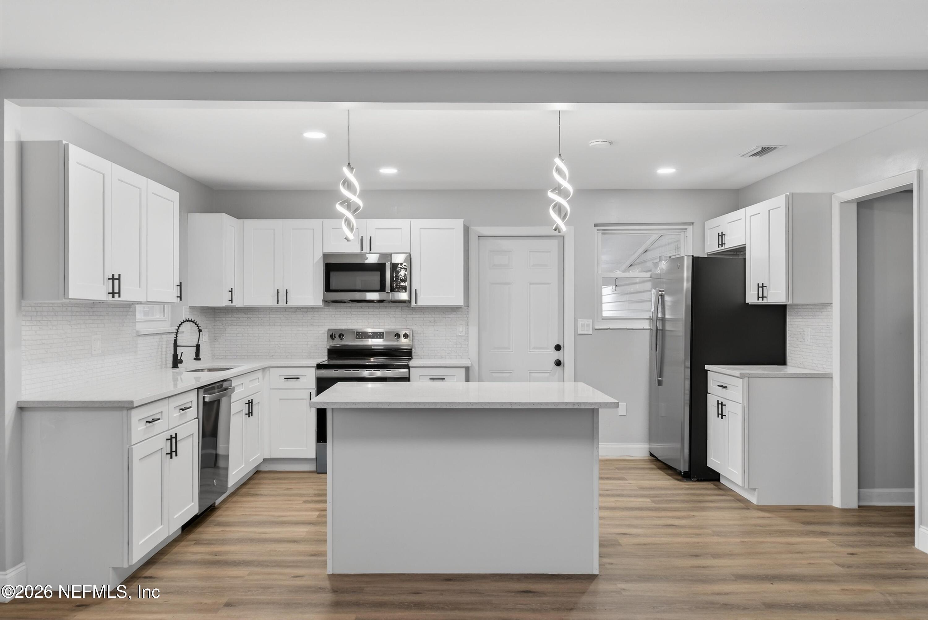 4725 Tango Lane West Jacksonville, FL 32210 - Photo 13 of 54 a kitchen with stainless steel appliances granite countertop a stove top oven a refrigerator a sink and dishwasher with wooden floor