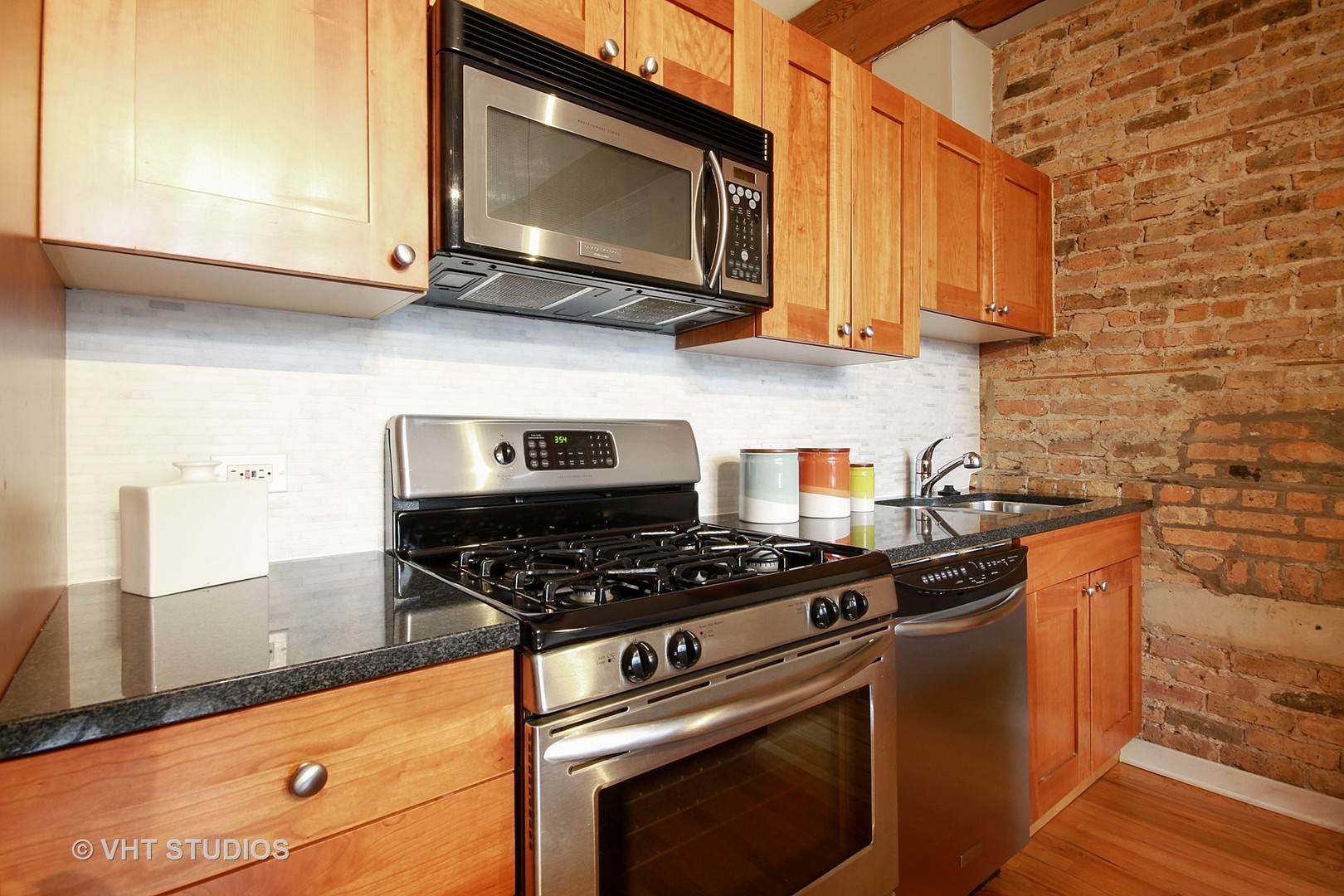 1344 West Madison Street, Unit 201 Chicago, IL 60607 - Photo 8 of 10 a kitchen with stainless steel appliances granite countertop a stove a microwave and cabinets