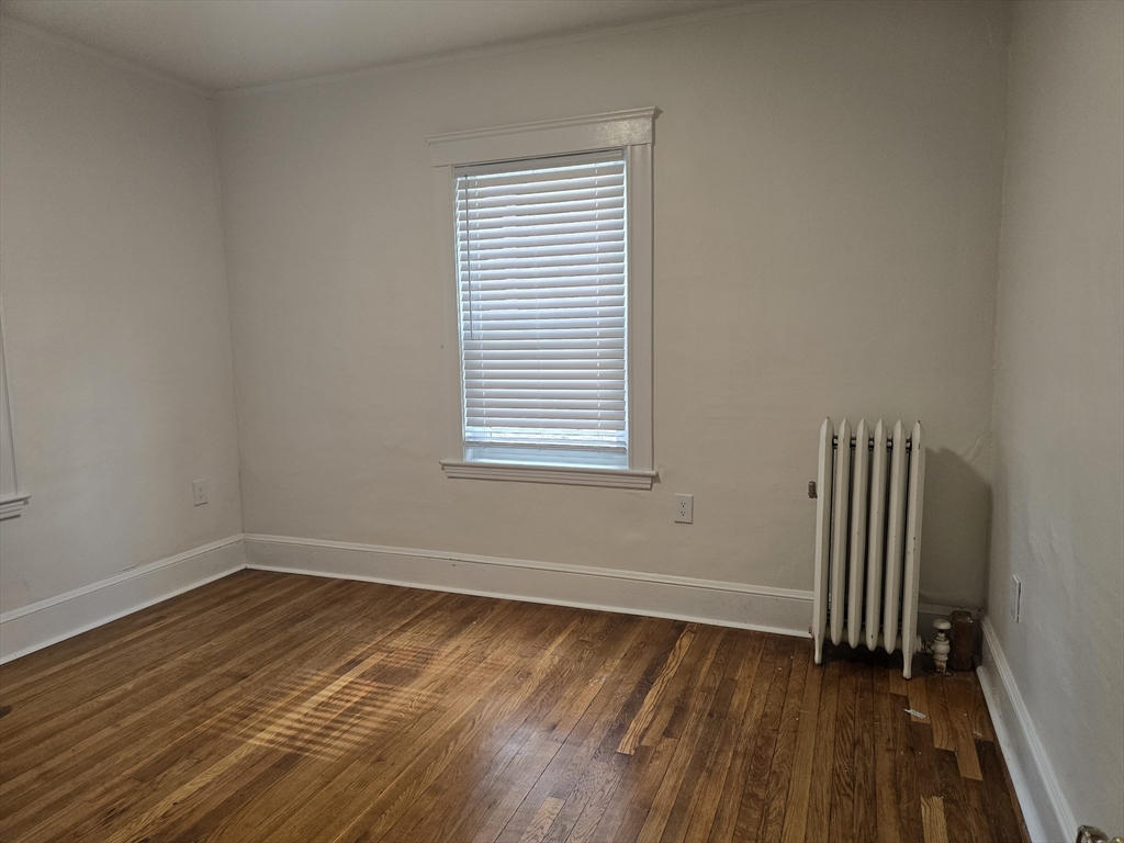 105 Fuller Street, Unit 1 Boston, MA 02124 - Photo 6 of 6 an empty room with wooden floor and windows