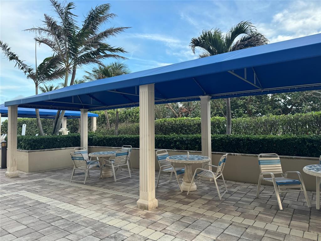 2000 South Ocean Boulevard, Unit 5P Lauderdale-by-the-Sea, FL 33062 - Photo 20 of 34 a view of a patio with a table chairs and a floor to ceiling window