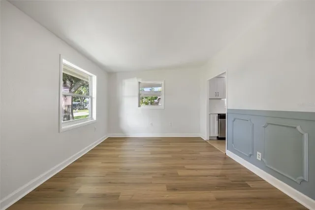 a view of an empty room with window and wooden floor
