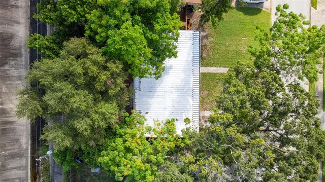 an aerial view of a house with a yard and large trees