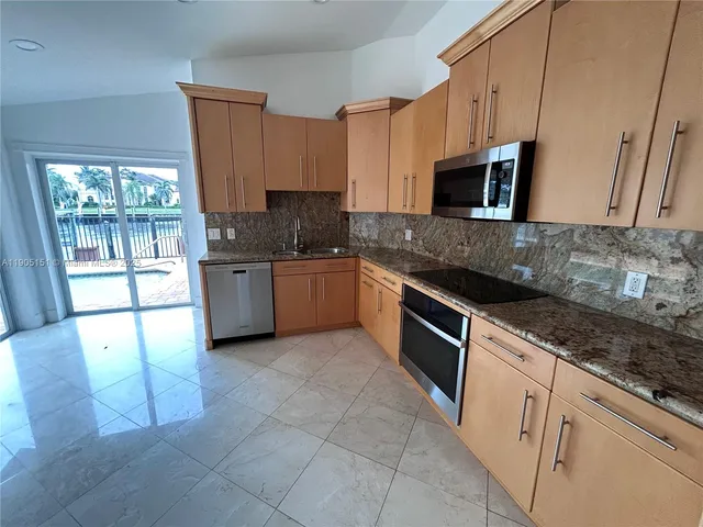 a large kitchen with stainless steel appliances granite countertop a stove a sink and a microwave