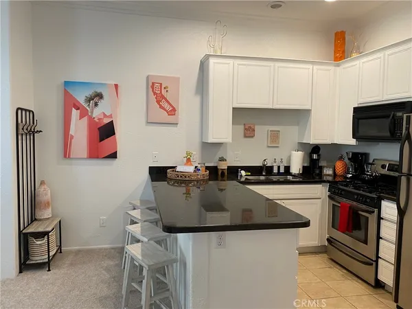 a kitchen with stainless steel appliances granite countertop a sink a stove a microwave a counter top space and cabinets