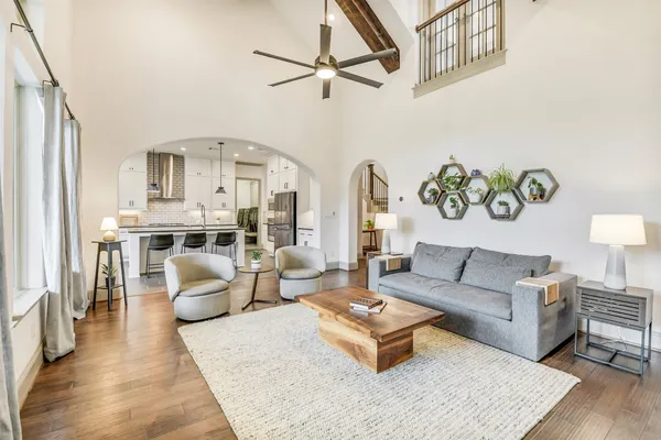 a living room with furniture kitchen view and a chandelier