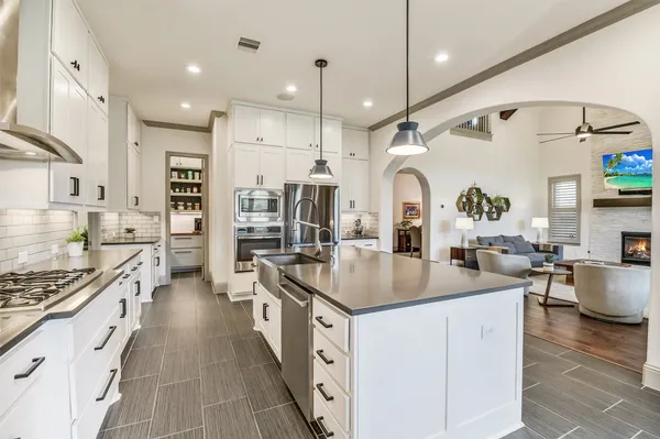 a kitchen with stainless steel appliances kitchen island granite countertop a dining table chairs and white cabinets