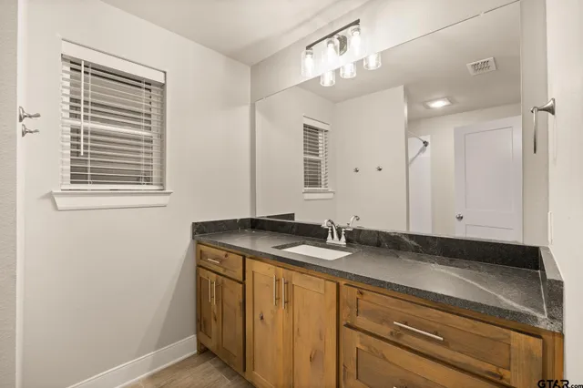 a bathroom with a granite countertop sink a mirror and a vanity