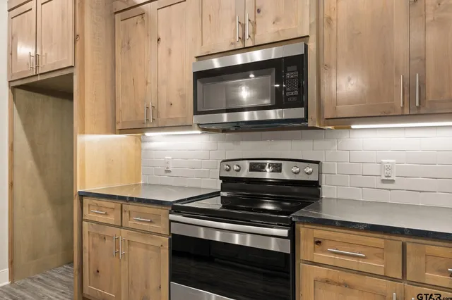 a kitchen with stainless steel appliances granite countertop white cabinets and a stove top oven