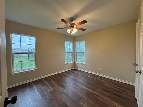 a view of an empty room with window and wooden floor