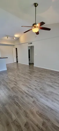 a view of a room with wooden floor and a ceiling fan