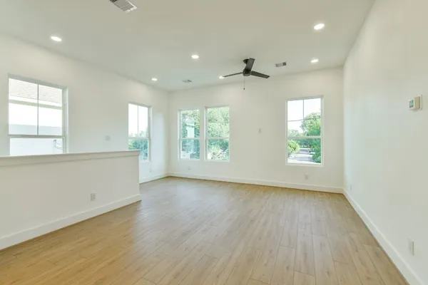 an empty room with wooden floor and windows
