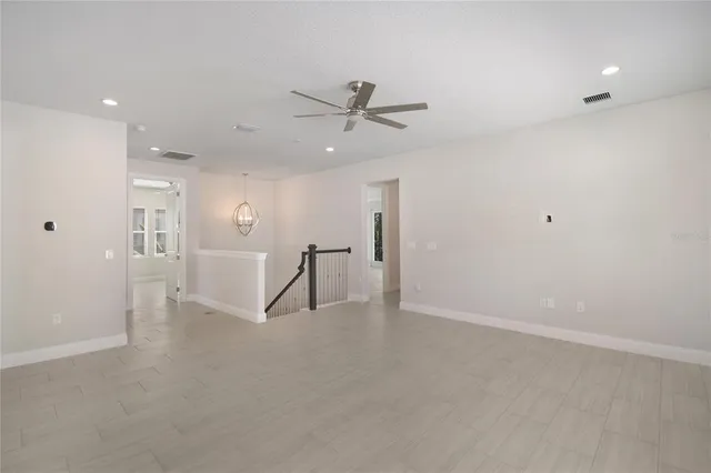 en empty room with windows and ceiling fan