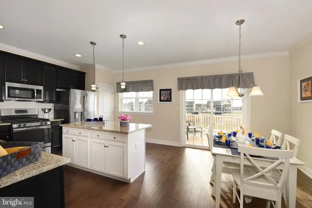 a kitchen with stainless steel appliances kitchen island granite countertop a stove a sink a dining table and chairs with wooden floor