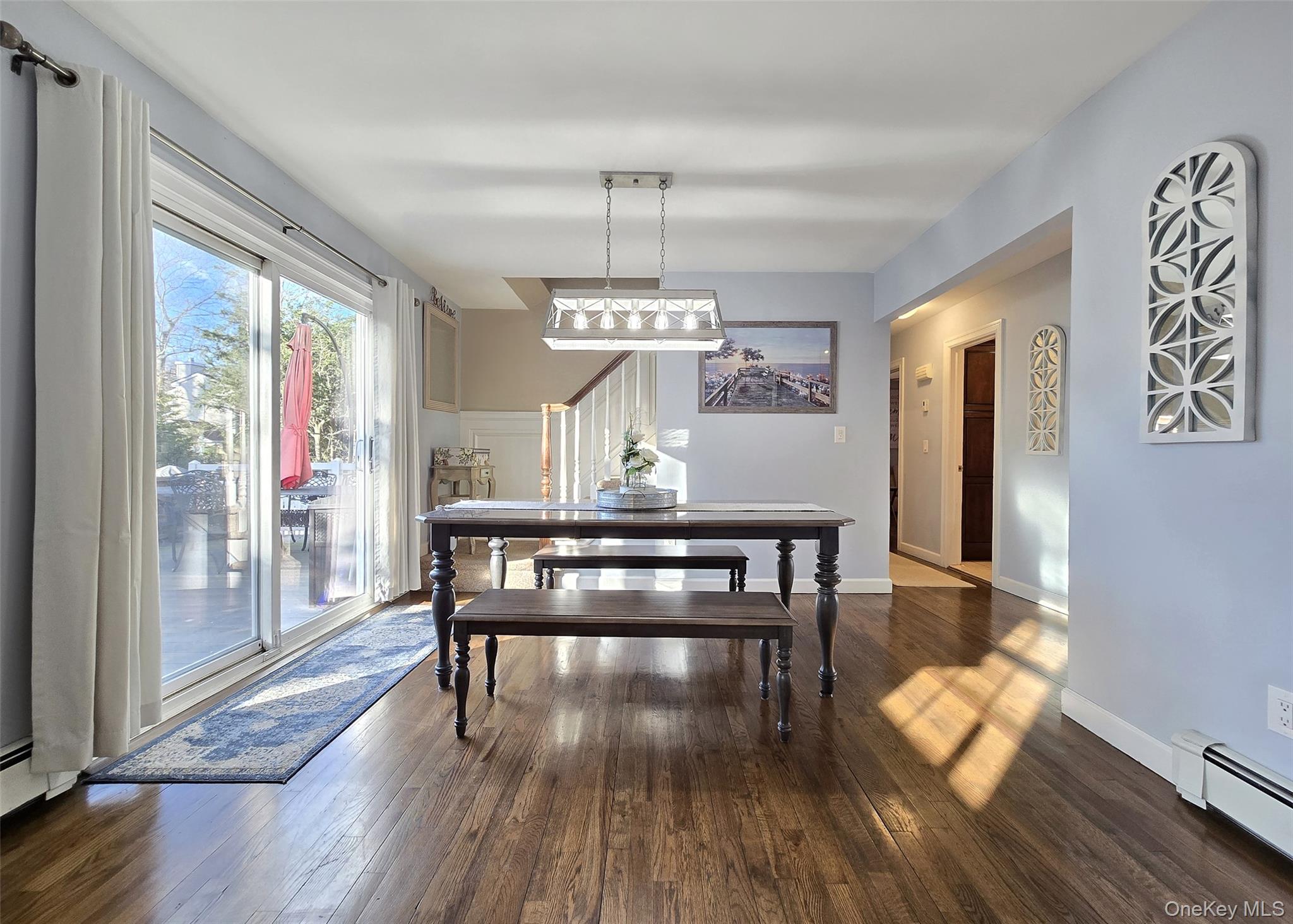 94 Clarendon Road Ronkonkoma, NY 11779 - Photo 4 of 31 a dining room with wooden floor a chandelier a wooden table and chairs