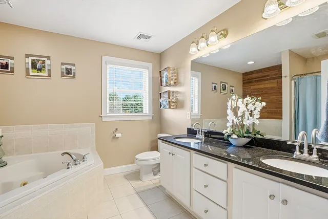 a bathroom with a granite countertop sink a toilet a large mirror and a bathtub