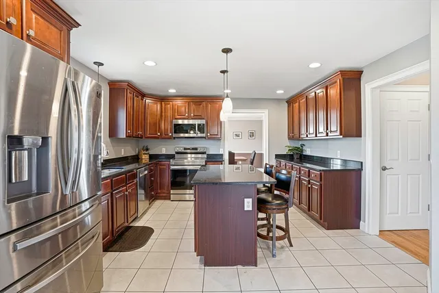 a kitchen with kitchen island granite countertop a stove a sink a refrigerator a dining table and chairs