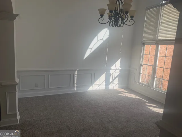 a view of empty room with windows and chandelier fan