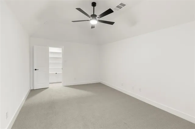 an empty room with windows and ceiling fan