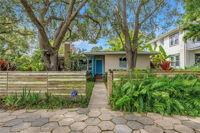 a front view of a house with garden and plants