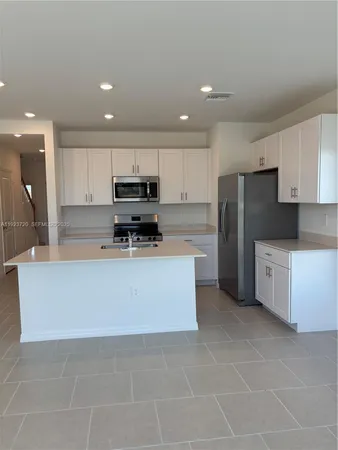a large kitchen with stainless steel appliances a refrigerator a stove top oven and a sink
