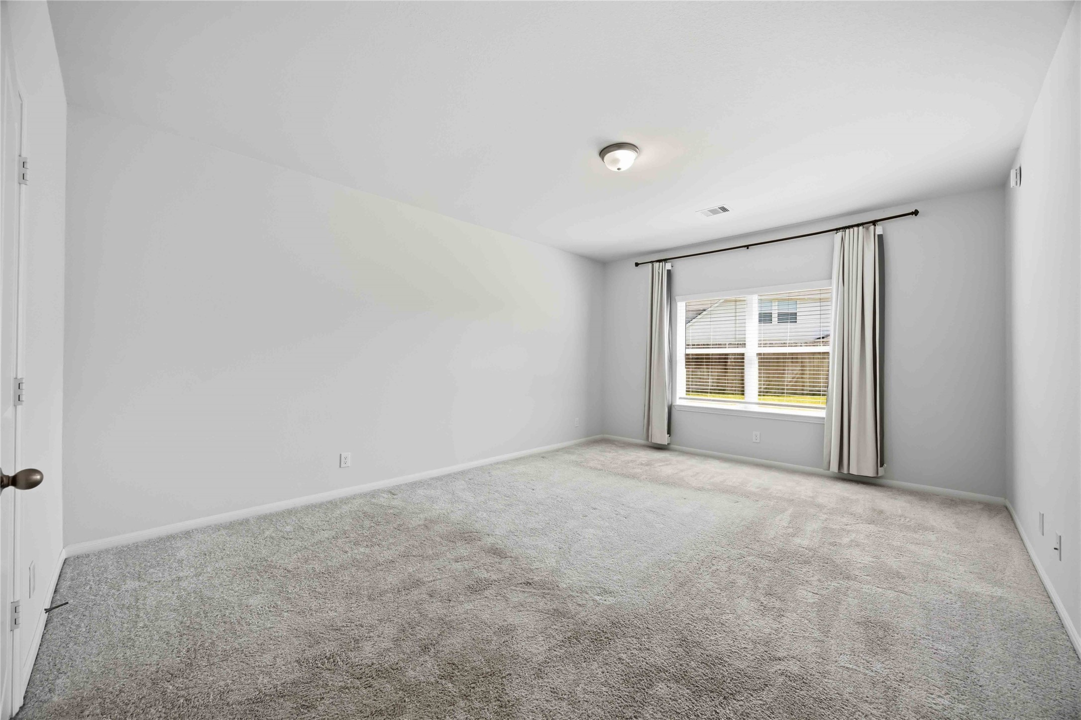 2402 Mount Dana Drive Rosharon, TX 77583 - Photo 13 of 28 Spacious and bright bedroom with plush carpeting, featuring a large window that lets in ample natural light, complemented by soft drapery.