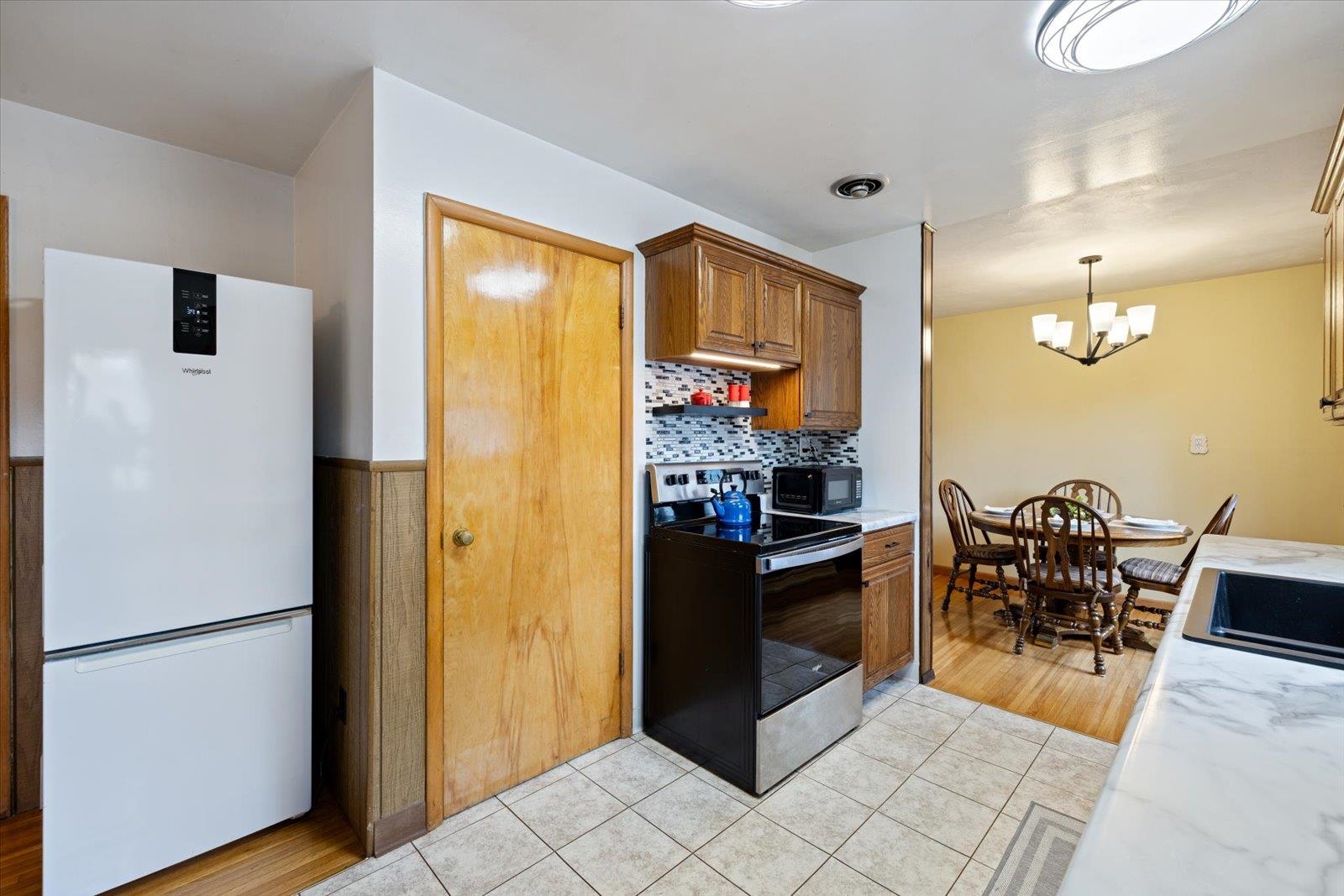 36 East Beacon Hill Road Ely, MN 55731 - Photo 7 of 30 Kitchen featuring freestanding refrigerator, electric range, backsplash, brown cabinetry, and light tile patterned floors