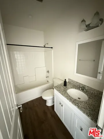 a bathroom with a granite countertop sink a toilet a mirror and shower