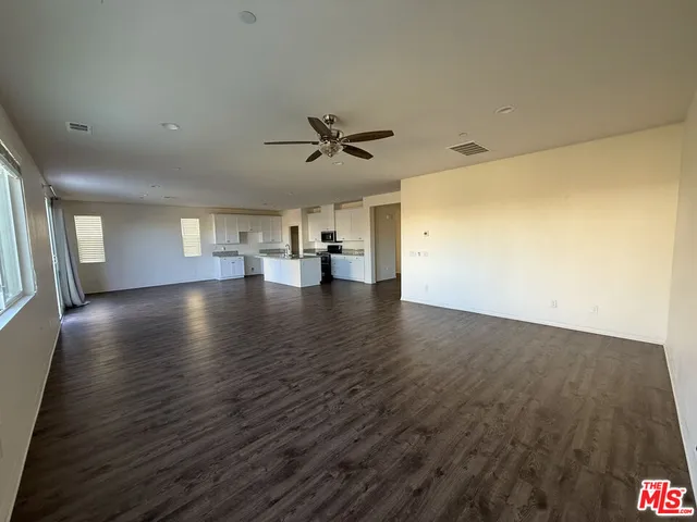 an empty room with wooden floor and a ceiling fan