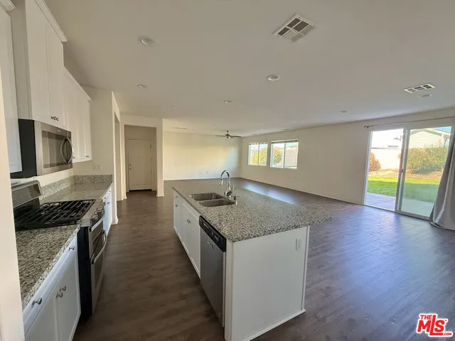 a kitchen with granite countertop stainless steel appliances a stove top oven and sink