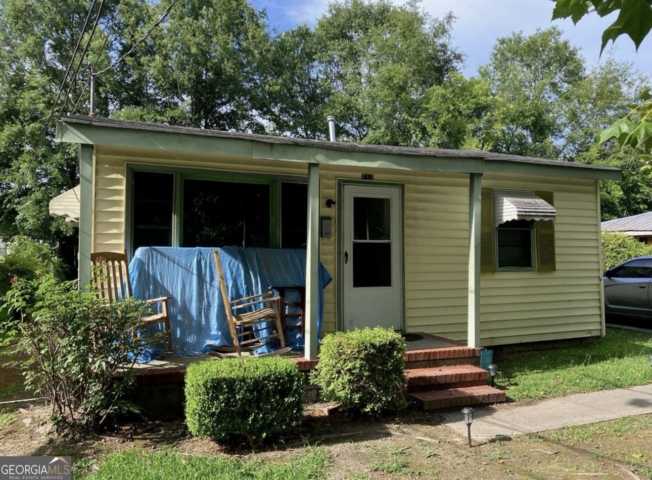 a view of a chair and table in the back yard of the house