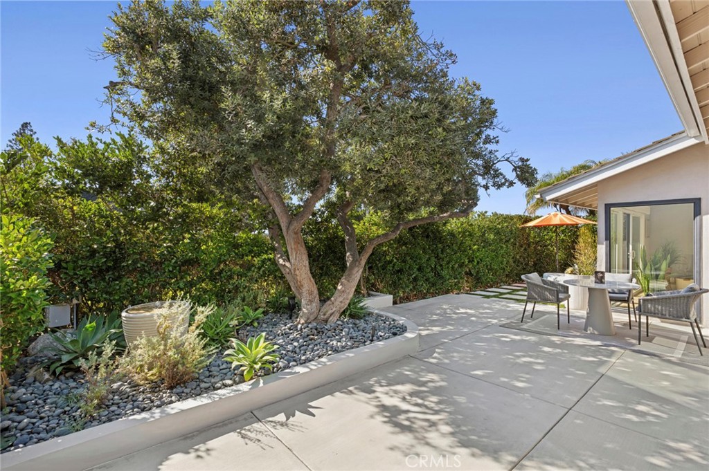 3 Rue Cannes Newport Beach, CA 92660 - Photo 25 of 46 Spacious backyard patio surrounded by mature landscaping, ideal for outdoor lounging and entertaining.