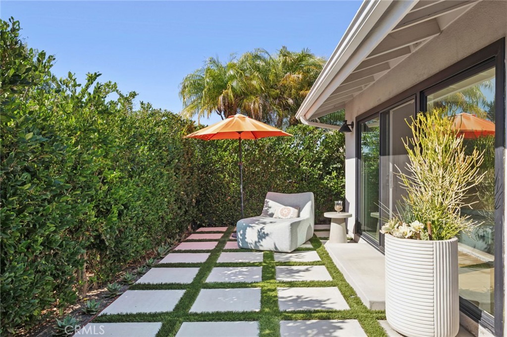 3 Rue Cannes Newport Beach, CA 92660 - Photo 26 of 46 Charming outdoor lounge space with modern paver design and lush privacy hedges, creating a peaceful setting to relax or enjoy morning coffee.